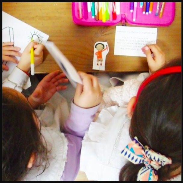 Chicas trabajando en un aula con lápices de colores y una figura de cartulina, en un taller escolar de Proyecto Caravana